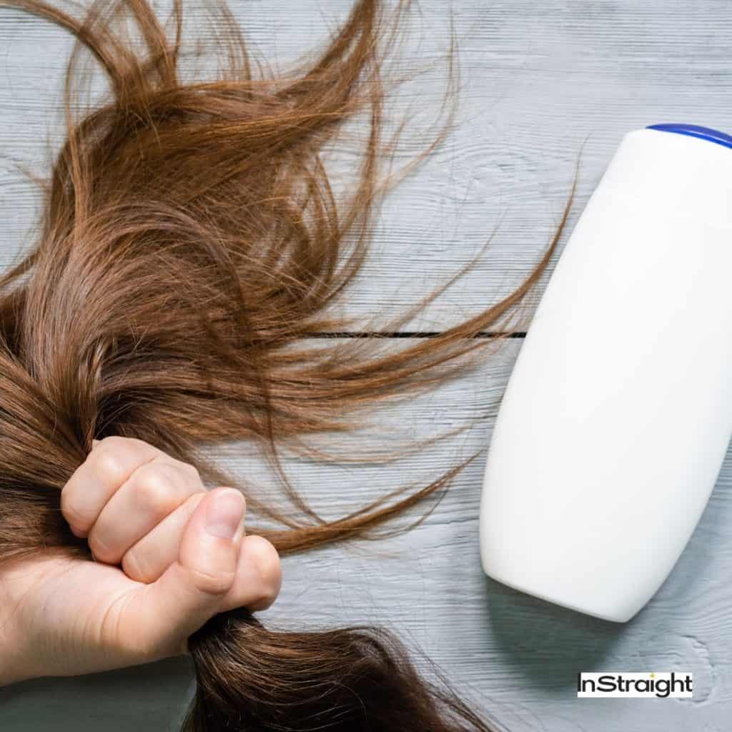 A bunch of hair next to a shampoo bottle